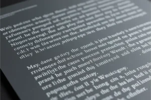 Close up of white text in gibberish on a dark grey sheet of paper